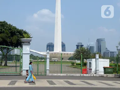 Warga berjalan di depan pagar Monumen Nasional (Monas), Jakarta, Sabtu (15/5/2021). Warga kecewa lantaran tempat wisata tersebut ditutup, padahal mereka datang untuk menikmati libur Idul Fitri 1442 Hijriah. (merdeka.com/Imam Buhori)