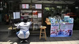Seorang perempuan mengisi “Pantry of Sharing” dengan barang-barang di Bangkok, Thailand, Rabu (13/5/2020). Warga mendirikan lemari dapur berisi mi instan, makanan kaleng, beras, dan sabun batangan di pinggir- pinggir jalan untuk membantu yang lain di tengah krisis Covid-19. (Lillian SUWANRUMPHA/AFP)