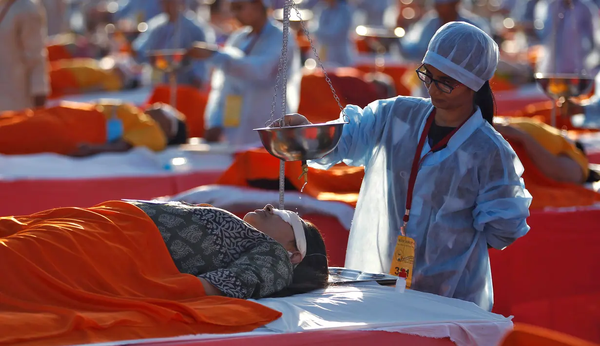 Seorang peserta mendapatkan Shirodhara massal, sebuah terapi Ayurveda dengan perlahan-lahan menuangkan minyak meditasi di dahi, di Ahmedabad, India, 24 Desember 2016. Terapi untuk memecahkan rekor dunia ini melibatkan 1.111 peserta. (REUTERS/Amit Dave)