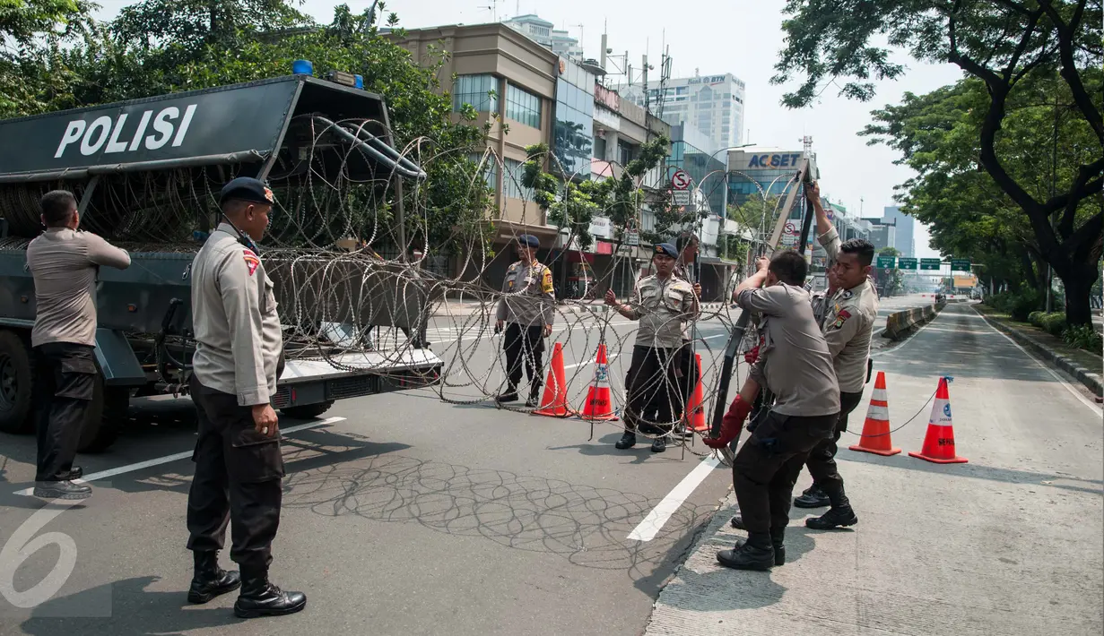 Aparat kepolisian menurunkan kawat berduri dari mobil di depan Istana Negara, Jakarta, Senin (1/5). Kawat berduri dipasang untuk mengantisipasi puluhan ribu buruh yang akan menggelar peringatan May Day di Istana Negara. (Liputan6.com/Gempur M Surya)