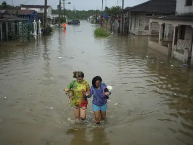 Warga menyeberangi jalan yang tergenang air akibat hujan yang disebabkan oleh Badai Idalia, di Batabano, Kuba, Selasa, 29 Agustus 2023. (AP Photo/Ramon Espinosa)