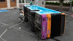 Seorang pria bekerja pada bus kota yang diubah menjadi kolam renang di Gosnay, Prancis Utara pada 15 Juli 2019. Karya seorang seniman Prancis, Benedetto Bufalino ini merupakan bus yang sudah dipensiunkan alias tak layak pakai untuk mengaspal di jalanan kota. (DENIS CHARLET / AFP)