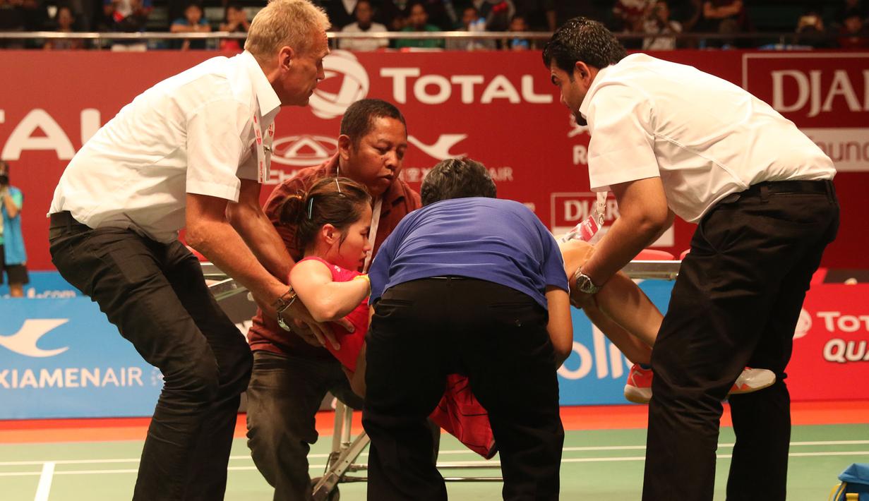 Ratchanok Intanon, dibawa keluar lapangan setelah mengalami cedera kaki kanan saat bertanding melawan pebulutangkis Indonesia, Lindaweni Fanetri. (Bola.com/Arief Bagus)