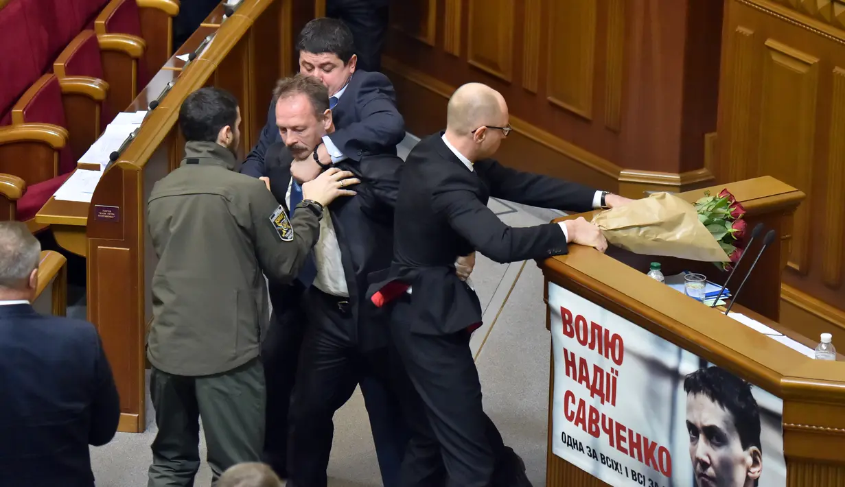 Sejumlah orang tampak menghalangi anggota parlemen bernama Oleg Barna yang tengah menyeret PM Arseny Yatsenyuk dari podium Majelis Tinggi Parlemen Ukraina, 11 Desember 2015. (REUTERS/Valentyn Ogirenko)