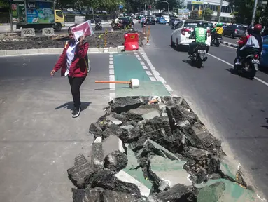 Pejalan kaki melintas di samping jalur sepeda yang di bongkar di kawasan Cikini, Jakarta, Selasa (19/11/2019). Jalur sepeda berumur 2 bulan tersebut dibongkar akibat proyek pelebaran trotoar. (Liputan6.com/Faizal Fanani)