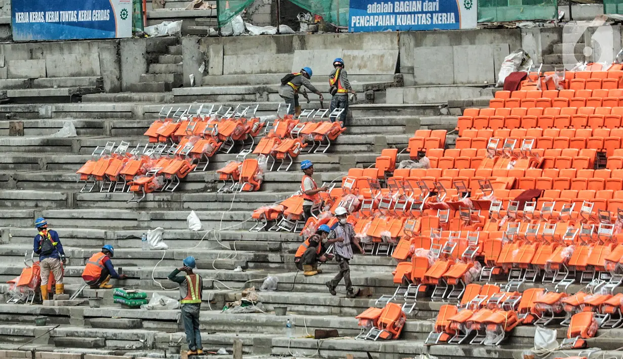 Pekerja saat menyelesaikan pemasangan bangku penonton di lapangan utama Jakarta International Stadium (JIS), Papanggo, Jakarta Utara, Selasa (7/12/2021). Progres pembangunan stadion sepakbola dengan kapasitas 82.000 penonton tersebut saat ini baru mencapai 87 persen. (merdeka.com/Iqbal S Nugroho)
