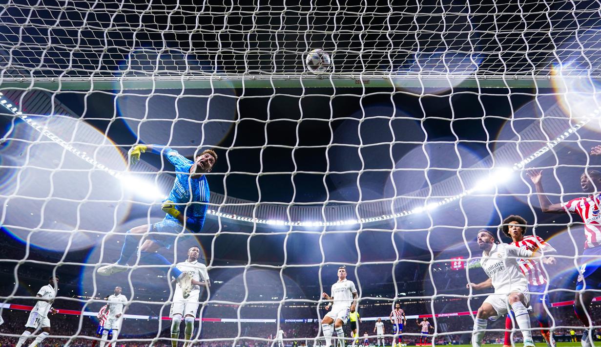 Penjaga gawang Real Madrid, Thibaut Courtois berusaha menepis bola saat bertanding melawan Atletico Madrid selama pertandingan lanjutan La Liga Spanyol di stadion Wanda Metropolitano di Madrid, Spanyol, Senin (19/9/2022).  Real Madrid asuhan Carlo Ancelotti kini masih sempurna dengan mengoleksi 18 poin dari enam laga. (AP Photo/Manu Fernandez)