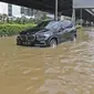 Sebuah mobil melintasi banjir di Jalan Ahmad Yani, Cempaka Putih, Jakarta, Minggu (23/2/2020). Banjir yang terjadi dari dini hari tadi melumpuhkan akses jalan tersebut. (Liputan6.com/Herman Zakharia)