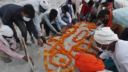 Keluarga berdoa setelah menguburkan jenazah di kuburan pasir dangkal di tepi sungai Gangga di Prayagraj, 16 Mei 2021. Polisi menjangkau penduduk desa di India utara untuk menyelidiki penemuan mayat yang terkubur di kuburan pasir dangkal atau terdampar di tepi Sungai Gangga. (AP Photo/Rajesh Kumar Si
