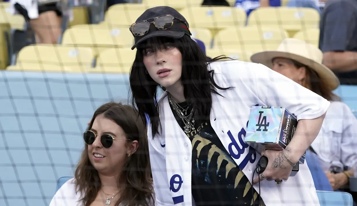 Penyanyi Billie Eilish duduk sebelum pertandingan bisbol antara Los Angeles Dodgers dan San Francisco Giants di Los Angeles, Amerika Serikat, 21 Juli 2022. Billie Eilish menyaksikan tim tuan rumah bangkit dari ketertinggalan untuk kemudian memenangkan pertandingan dengan skor 9-6. (AP Photo/Marcio Jose Sanchez)