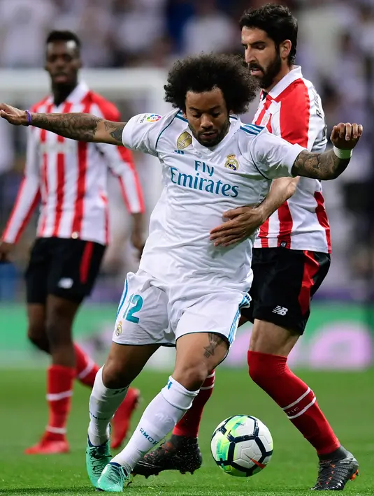 Bek Real Madrid, Marcelo berebut bola dengan gelandang Athletic Bilbao, Raul Garcia pada pekan ke-33 La Liga di Santiago Bernabeu, Rabu (18/4). Menjamu Athletic Bilbao, Real Madrid harus puas bermain imbang 1-1. (JAVIER SORIANO/AFP)