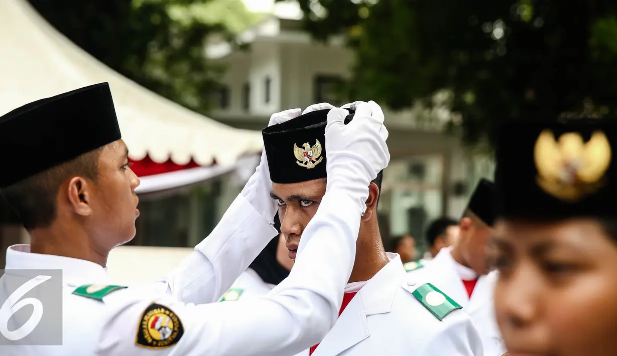 Anggota Paskibraka 2016 merapikan peci rekannya saat bersiap melaksanakan gladi bersih Upacara HUT ke-71 Kemerdekaan RI di Istana Merdeka, Jakarta, Senin (15/8). (Liputan6.com/Faizal Fanani)
