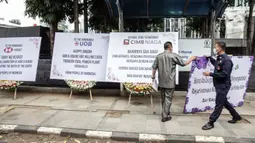 Security menurunkan karangan bunga di depan Kantor Adaro, Jakarta, Senin (3/5/2021). Karangan bunga dikirim sebagai tanda duka cita mendalam karena telah memperparah krisis iklim dengan membiayai produsen batu bara terbesar kedua di Indonesia. (Liputan6.com/Faizal Fanani)