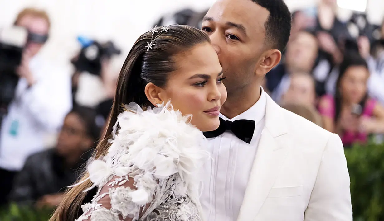 John Legend pun memberikan ciuman manis untuk Chrissy Teigen dalam busana senada berwarna putih. (REX/Shutterstock/HollywoodLife)