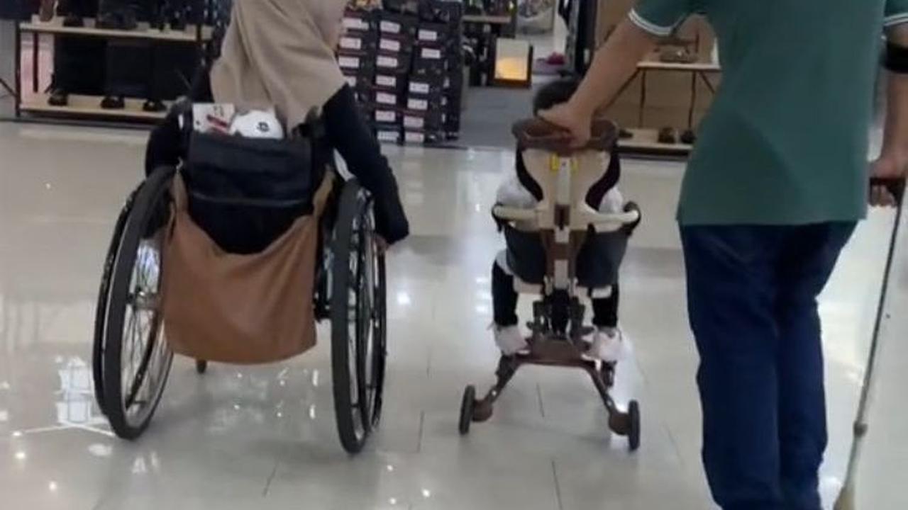 Beginilah gambaran ketika kedua orang tua disabilitas mengajak putrinya jalan-jalan di mall. Sang istri memakai kursi roda, sementara sang suami memakai tongkat sambil mendorong sepeda roda tiga putrinya.