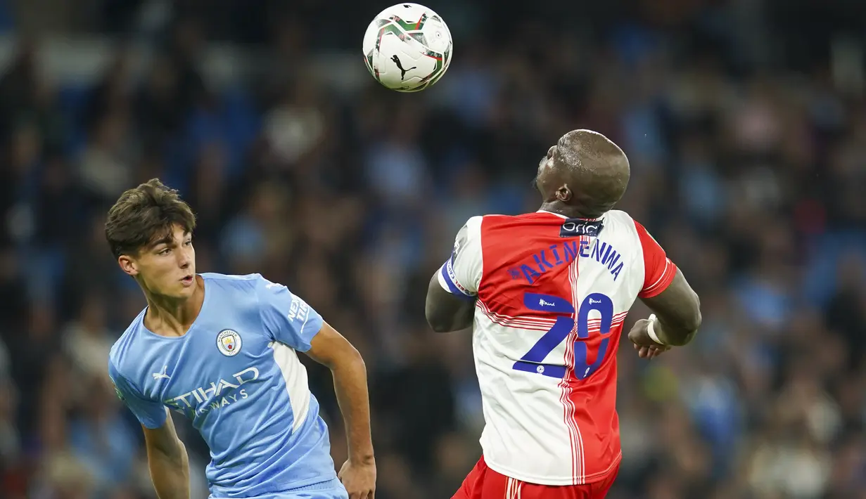 Penyerang Wycombe Wanderers, Adebayo Akinfenwa dan bek Manchester City, Finlay Burns berebut bola pada babak ketiga Piala Liga Inggris di Etihad Stadium, Rabu (22/9/2021) dini hari WIB. Manchester City menang telak 6-1 saat menjamu klub divisi tiga Wycombe Wanderers. (AP Photo/Dave Thompson)