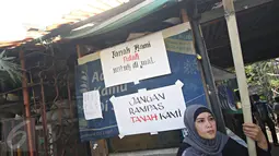 Seorang ibu duduk di dekat poster penolakan penggusuran di Jalan Lauser, RT 08/08, Kebayoran Baru, Jakarta, Senin (9/5). Warga melakukan penjagaan lantaran isu akan ada penyampaian SP-2 terkait penggusuran di lokasi itu. (Liputan6.com/Immanuel Antonius)