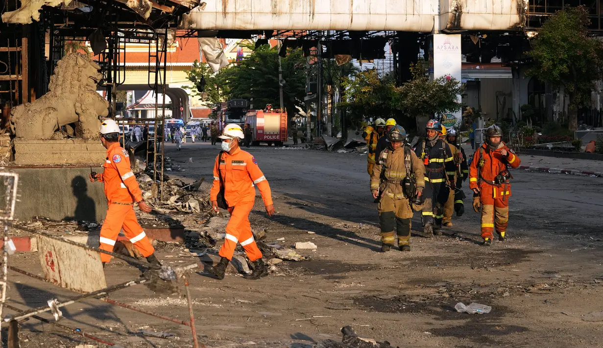 Pakar penyelamat Kamboja dan Thailand berjalan melalui reruntuhan bangunan untuk operasi pencarian di lokasi kebakaran besar kasino hotel Kamboja di Poipet, Kamboja, Jumat (30/12/2022). Pihak berwenang Thailand mengatakan bahwa lebih dari 50 orang dirawat di rumah sakit di Sa Kaeo, di mana 13 di antaranya menggunakan alat bantu hidup atau life support. (AP Photo/Heng Sinith)