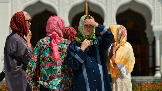 Turis asing mengenakan jilbab saat mengunjungi Masjid Agung Baiturrahman di Banda Aceh, Aceh pada 6 Agustus 2019. Selain sebagai tempat ibadah, Masjid Baiturahman juga menjadi tempat wisata bagi turis lokal dan mancanegara. (CHAIDEER MAHYUDDIN / AFP)