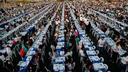 Ribuan orang yang terdiri dari warga Lebanon beserta yatim piatu dan pengungsi Suriah  berkumpul di sekitar meja-meja Iftar di Beirut Waterfront, Lebanon (9/6). Buka puasa bersama ini diikuti oleh 5.400 orang. (AP Photo / Hussein Malla)