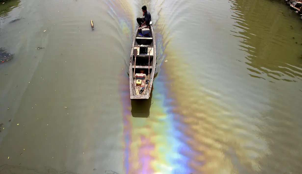 Seorang pria mengendarai perahu di sepanjang sungai yang tercemar oleh bahan bakar di Shaoxing, Zhejiang, Tiongkok pada 29 April 2015. Pertumbuhan industri dan kurangnya kesadaran lingkungan membuat saluran air terkontaminasi (REUTERS / Stringer)