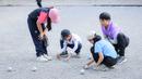 Anak-anak sedang mengukur hasil lemparannya saat bermain olahraga Petanque di Lapangan Latih Dua Kompleks 700th Anniversary of Chiang Mai Stadium, Kamis (11/12/2025).