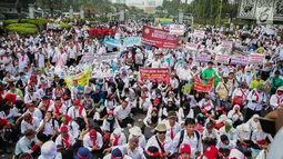 Massa membawa berbagai atribut dalam aksi damai di depan Istana Negara, Jakarta, Rabu (19/7). Mereka mendesak agar para pegawai non PNS yang telah mengabdi pada garda depan pelayanan publik, bisa diangkat menjadi PNS. (Liputan6.com/Faizal Fanani)