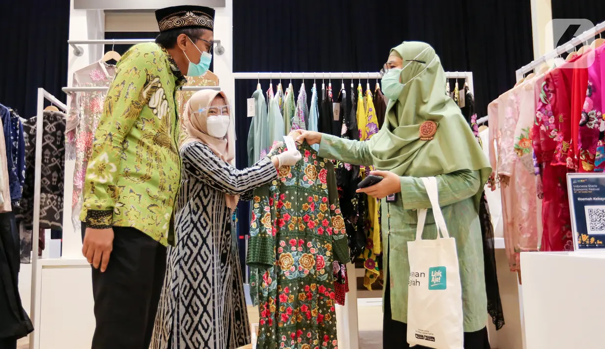 Chief Marketing Officer LinkAja Wibawa Prasetyawan (kiri) dan Direktur Departemen Ekonomi dan Keuangan Syariah Bank Indonesia, Ita Rulina (kanan) melihat baju muslim pada SEF ke-8 Tahun 2021 di JCC Senayan, Jakarta, Rabu (27/10/2021). (Liputan6.com/Fery Pradolo)