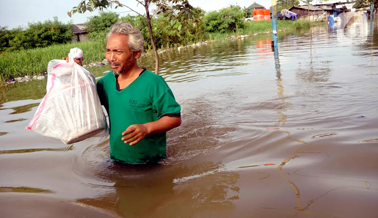 Seorang pria menerjang banjir yang melanda Perumahan Total Persada, Periuk, Kota Tangerang, Selasa (4/2/2020). Banjir akibat tanggul kali Ledug jebol membuat ratusan rumah di Total Persada terendam banjir hingga mencapai 3,5 meter. (merdeka.com/Arie Basuki)