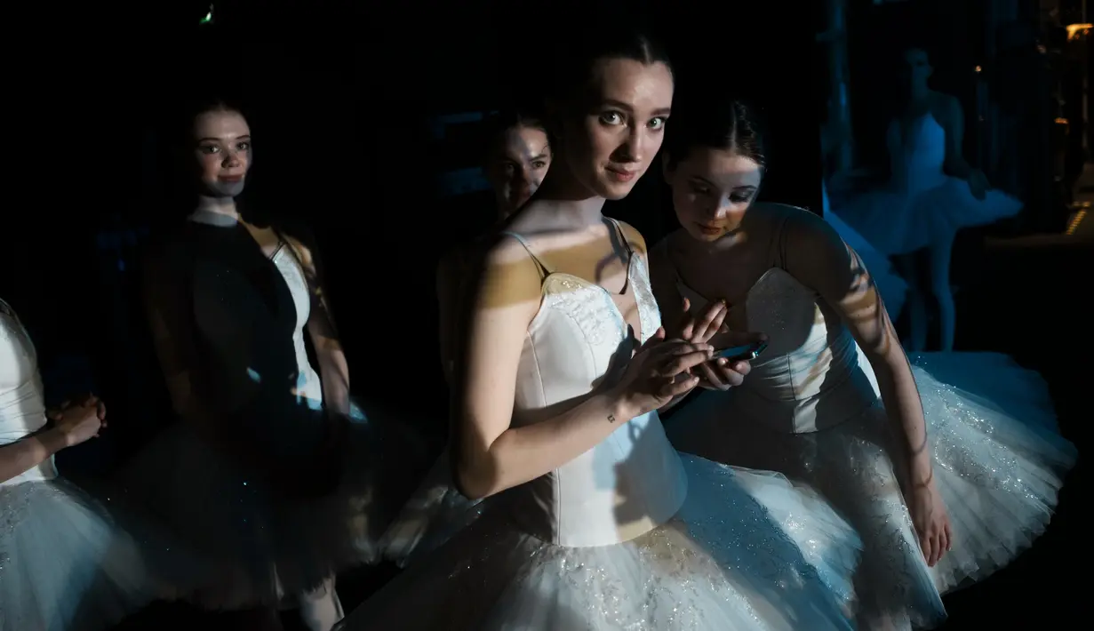 Penari Ukraina dari Balet Kota Kiev menonton smartphone di belakang panggung selama pertunjukan di Theatre de Chatelet, di Paris (8/3/2022). Balet Kota Kiev menari dengan penuh semangat di Paris untuk pertunjukan terakhir dari tur Prancis. (AP Photo/Thibault Camus)