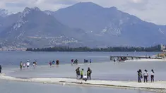 Wisatawan menyeberangi bentangan antara daratan dan pulau San Biagio di Manerba, di Danau Garda, Italia, Jumat, 14 April 2023. (AP Photo/Luca Bruno)