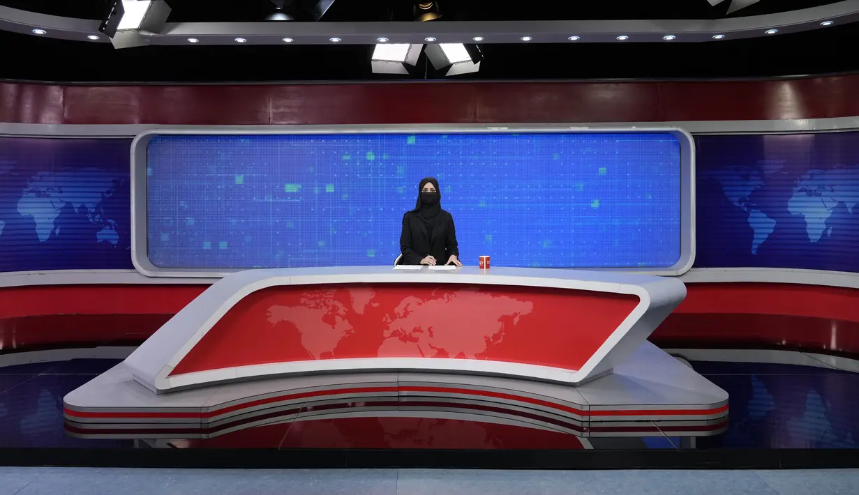 <p>Khatereh Ahmadi, seorang presenter televisi mengenakan penutup wajah saat membacakan berita di TOLO NEWS, di Kabul, Afghanistan, Minggu, 22 Mei 2022. Taliban mulai mewajibkan semua presenter atau pembawa acara televisi perempuan menutupi wajah mereka saat siaran. (AP Photo/Ebrahim Noroozi)</p>