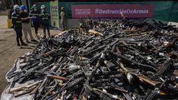 Pekerja berdiri di atas senjata yang secara sukarela diserahkan ke polisi atau disita, sebelum dilebur di Santiago, Chile, Kamis (11/11/2021). Lebih dari 13.600 senjata ilegal dihancurkan, menurut komisi nasional yang mengatur senjata. (AP Photo/Esteban Felix)