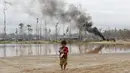 Seorang anak membawa anjingnya di depan kamp pertambangan emas ilegal yang dihancurkan polisi di zona Mega 14, Madre de Dios, Amazon selatan, Peru, (13/7/2015). Tambang emas ilegal ini termasuk dalam wilayah cagar alam hutan Amazon. (REUTERS/Janine Costa)