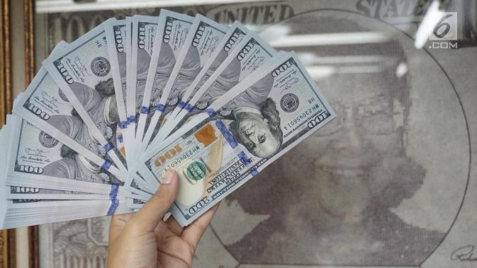 Teller menunjukkan mata uang dolar AS di penukaran uang di Jakarta, Rabu (10/7/2019). Nilai tukar rupiah terhadap dolar Amerika Serikat (AS) ditutup stagnan di perdagangan pasar spot hari ini di angka Rp 14.125. (Liputan6.com/Angga Yuniar)