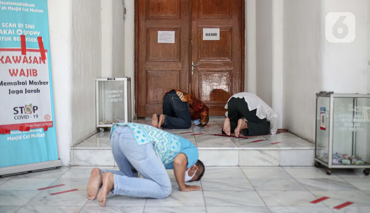 Sejumlah warga melaksanakan salat zuhur di halaman depan Masjid Cut Meutia, Jakarta, Jumat (18/9/2020). Pemprov DKI Jakarta kembali meniadakan kegiatan ibadah salat Jumat dan salat lima waktu berjemaah di semua Masjid Raya selama PSBB. (Liputan6.com/Faizal Fanani)