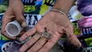 Seorang pria menunjukkan benda yang ditemukan setelah mengambilnya dari lumpur di saluran pembuangan limbah di Sungai Guaire, di Caracas, (1/2). (AFP Photo/Federico Parra)