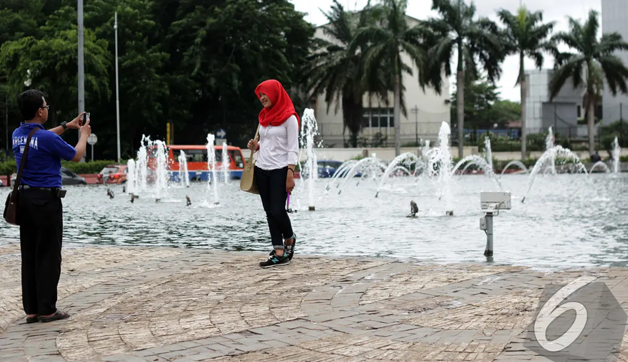 Seorang pengunjung mengabadikan gambarnya di Bundaran Hotel Indonesia (HI), Jakarta, Kamis (1/1/2015). (Liputan6.com/Faizal Fanani)