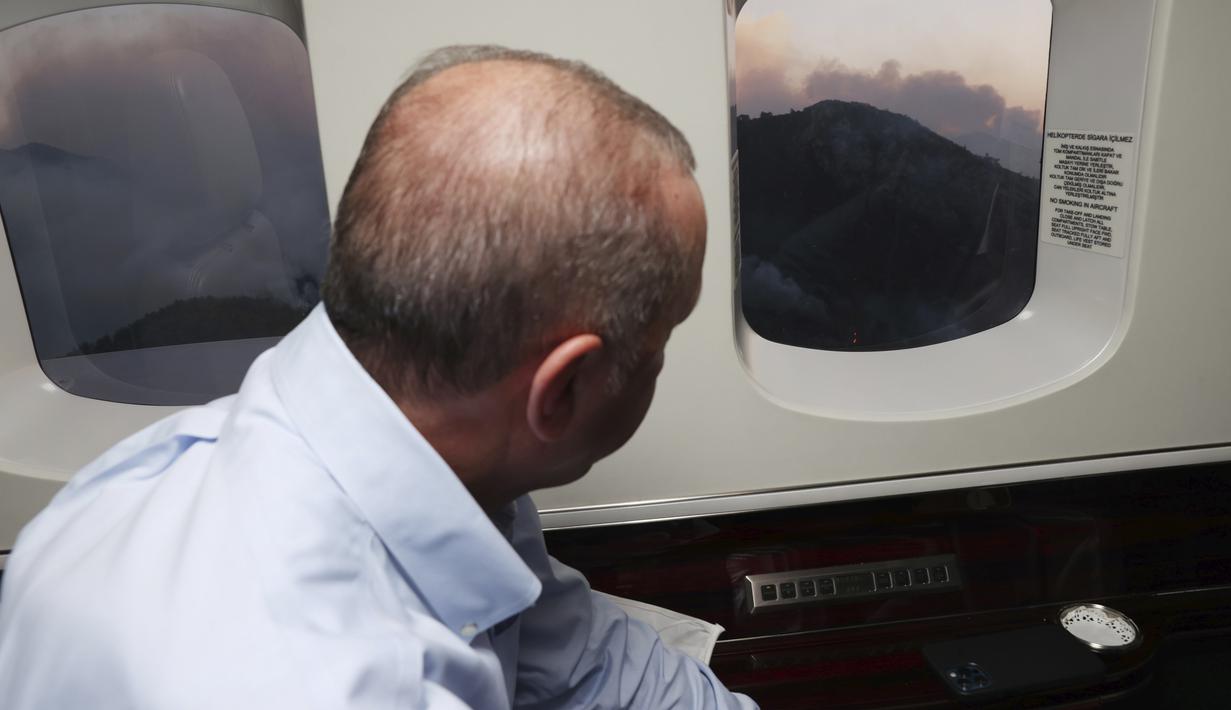 Presiden Turki Recep Tayyip Erdogan melihat dari pesawatnya ke kebakaran hutan di Marmaris, Mugla, Turki (31/7/2021). Kebakaran di seluruh Turki sejak Rabu membakar hutan, merambah desa dan tujuan wisata dan memaksa orang untuk mengungsi. (Turkish Presidency via AP, Pool)