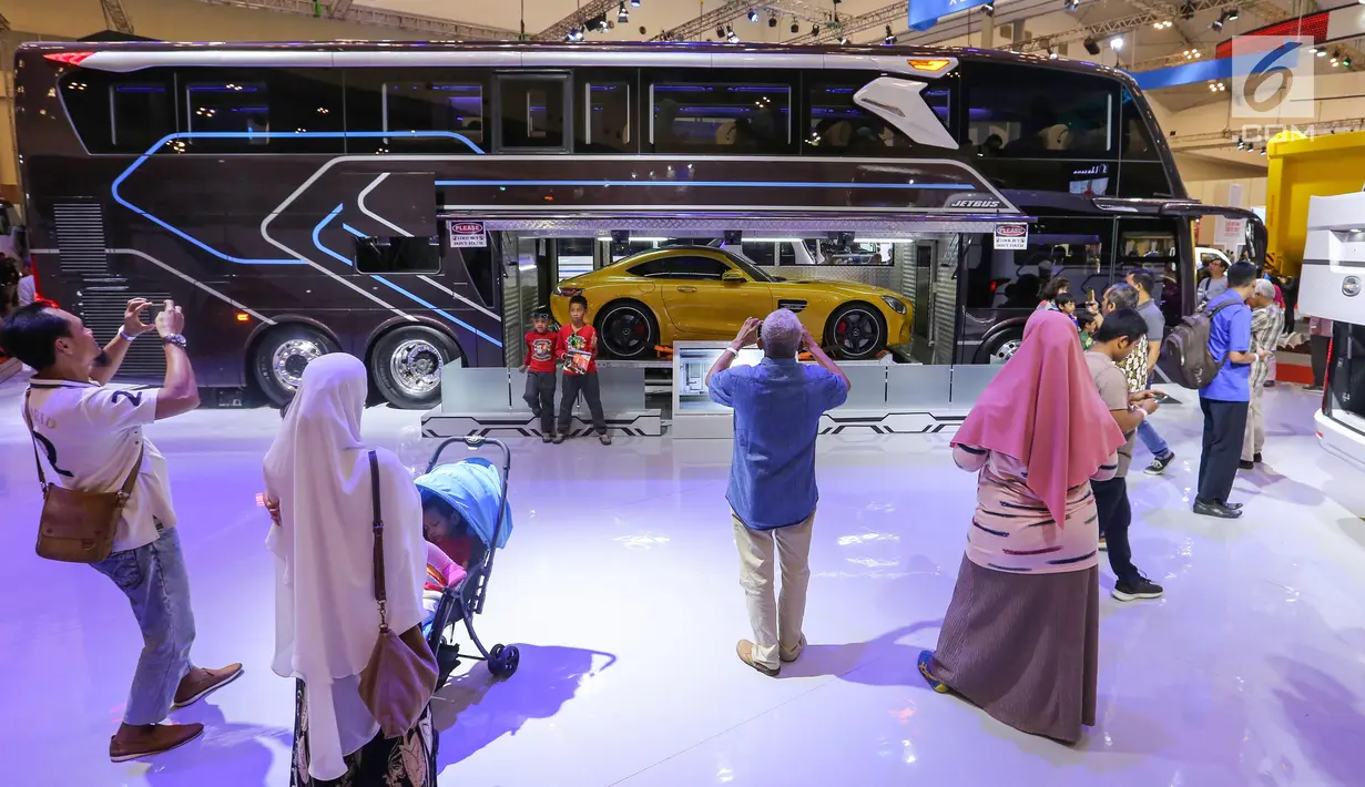 Pengunjung mengambil foto bus single doubel decker (SDD) yang mengangkut mobil sport dalam gelaran GIIAS 2019 di ICE BSD, Tangerang, Jumat (19/9/2019). Bus SDD, Adiputro memiliki sistem entertainment berupa smart tv, subwoofers, 10 speakers, preamplifier dan DVD player. (Liputan6.com/Ferbian Pradolo