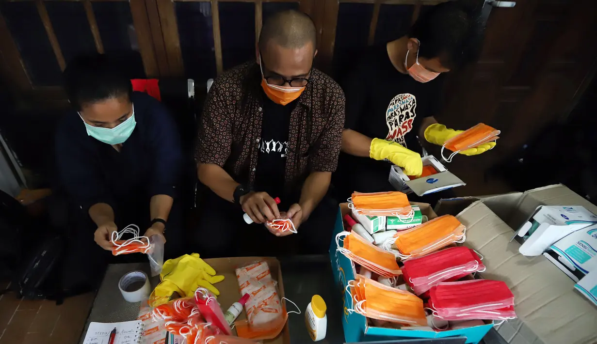 Ketua Pewarta Foto Indonesia (PFI) Reno Esnir (tengah) merapikan masker dan hand sanitizer untuk dibagikan kepada jurnalis foto di Jakarta, Jumat (20/3/2020). Pembagian secara gratis ini dilakukan untuk mengantisipasi penyebaran virus corona COVID-19. (Foto: Dok. Pewarta Foto Indonesia)
