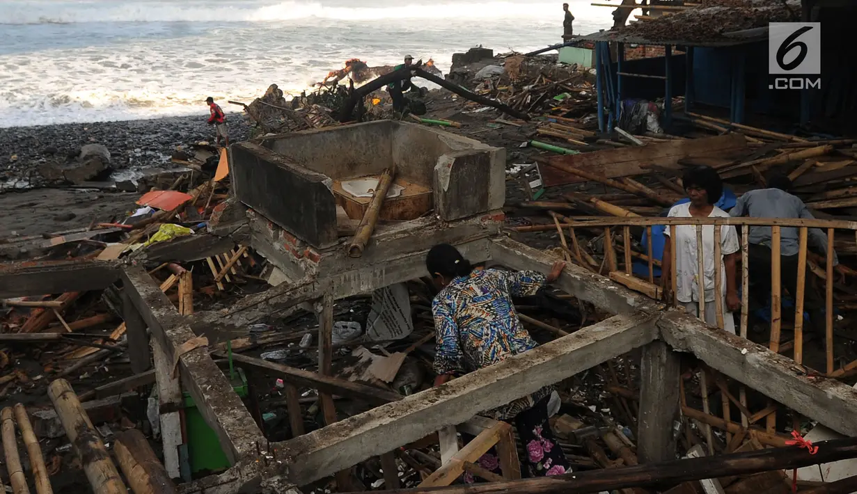 Warga mencari puing bangunan permanen yang hancur akibat terjangan ombak pasang di Karanghawu, Pelabuhan Ratu, Sukabumi (29/7). Gelombang pasang juga menyebabkan abrasi karena tanggul penahan ombak yang dibuat warga rusak berat. (Merdeka.com/Arie Basuki)