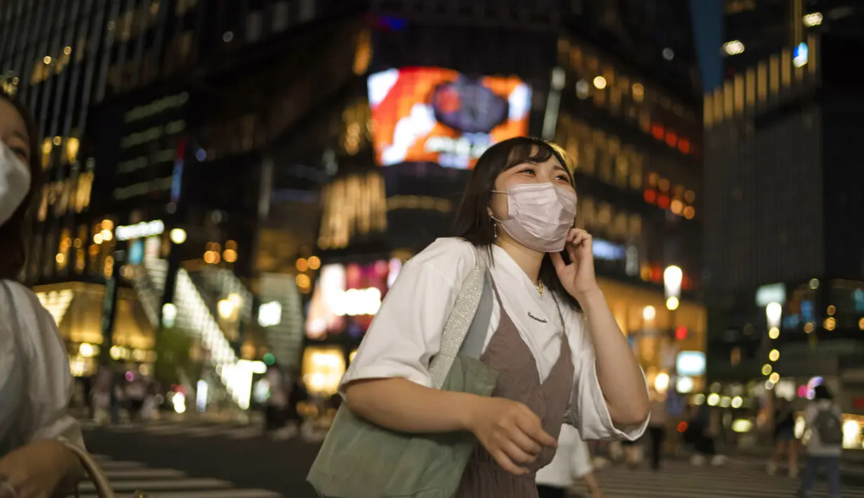 Seorang wanita mengenakan masker melintasi persimpangan di distrik perbelanjaan Ginza Tokyo, Kamis (23/9/2021). Di tempat ini terdapat berbagai toko serba ada, butik, restoran dan kafe. (AP Photo/Hiro Komae)