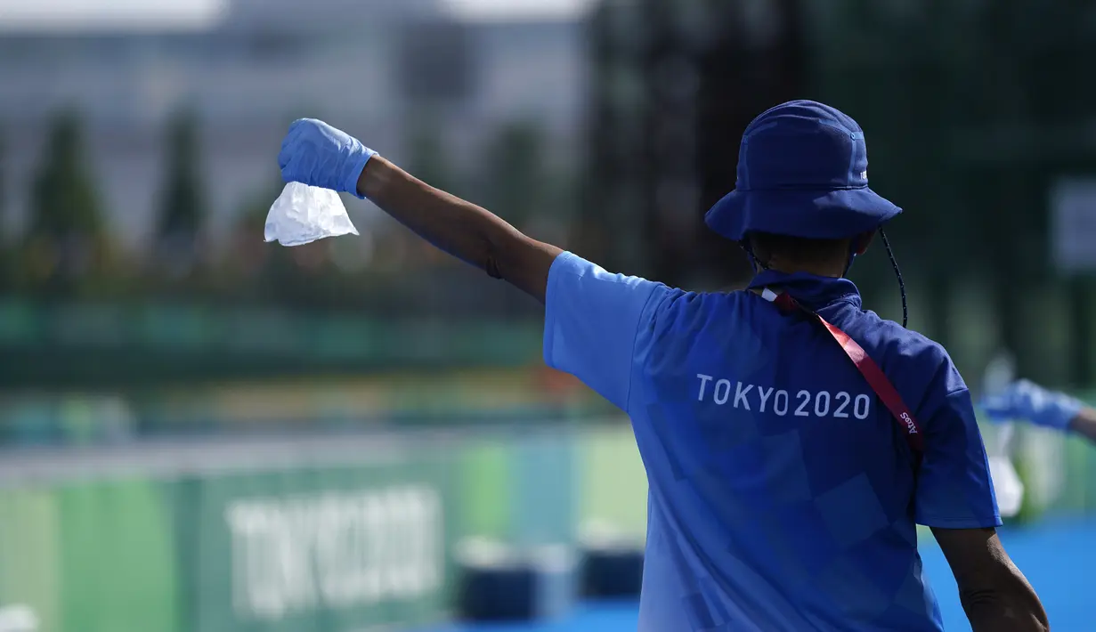 Seorang sukarelawan mengulurkan sekantong es untuk atlet selama triathlon individu putra Olimpiade Tokyo 2020, di Tokyo pada 26 Juli 2021. Relawan atau volunteer merupakan salah satu kunci suksesnya suatu perhelatan, tak terkecuali Olimpiade Tokyo 2020 ini.  (AP/Jae C.Hong)