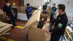 Rodolfo Gomez dan karyawannya mendemonstrasikan desain kardus mereka dapat berfungsi sebagai tempat tidur rumah sakit dan peti mati untuk pasien COVID-19 di Bogota, Kolombia, Jumat (8/5/2020). Perusahaan ini menanggapi kekurangan tempat tidur dan peti mati selama pandemi.  (AP/Fernando Vergara)