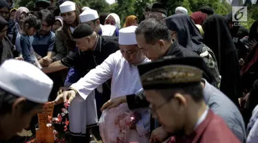 Penyanyi religi Opick menaburkan bunga usai memakamkan almarhum istri keduanya Wulan Mayasari di TPU Semper, Jakarta, Senin (19/3). Diiringi shalawat nabi dan tahlil, Opick memakamkan istrinya dengan wajah yang tegar. (Liputan6.com/Faizal Fanani)