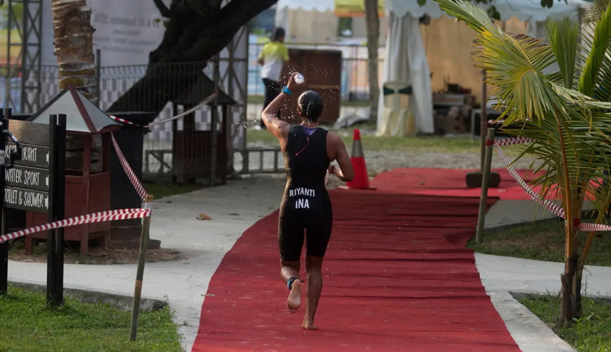 Peserta menyiram air saat berlari selama Rhino Cross Triathlon 2018 di Kawasan Tanjung Lesung, Pandeglang, Banten, Minggu (30/9). Rhino Cross Triathlon diikuti lebih dari 200 peserta dari dalam negeri dan manca negara. (Liputan6.com/HO/Nick Hanoatubun)