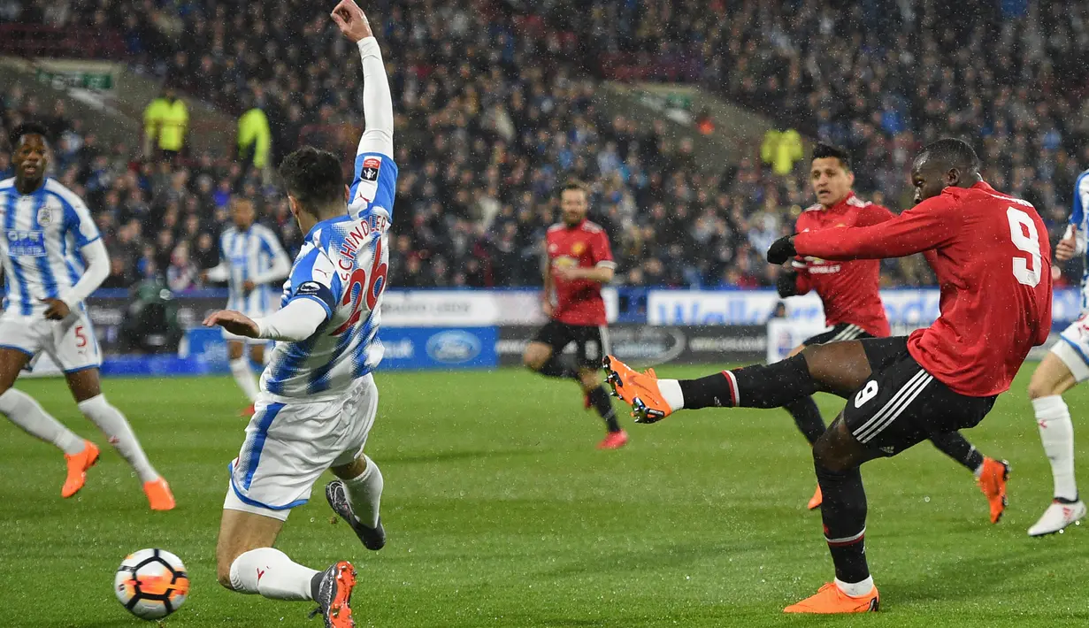 Striker Manchester United, Romelu Lukaku (kanan) mencetak gol ke gawang Huddersfield Town dalam pertandingan putaran kelima Piala FA di John Smith's Stadium, Minggu (18/2). Lukaku memborong dua gol kemenangan MU. (Oli SCARFF/AFP)