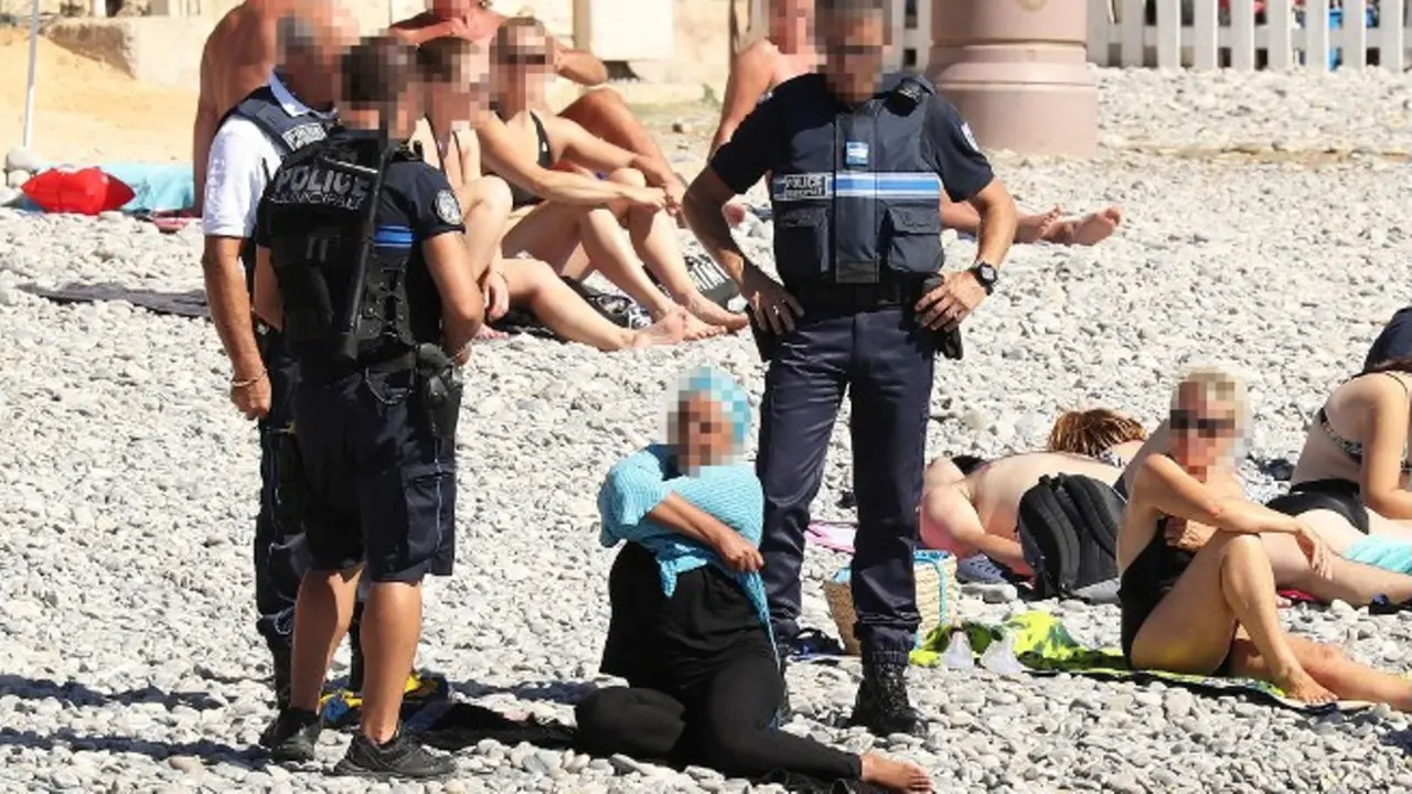 Foto polisi menjatuhkan denda pada perempuan yang mengenakan burkini memicu kontroversi di Prancis