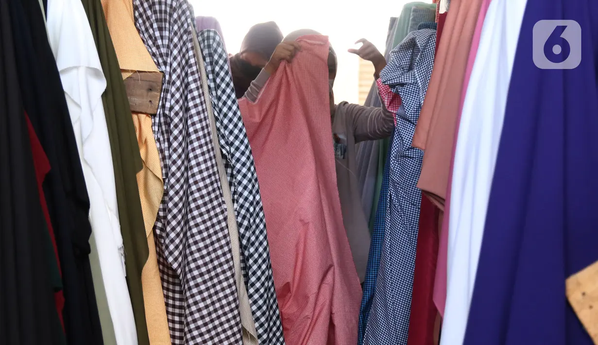 Pedagang menata bahan kain yang akan dijual di kawasan Tangerang, Banten, Sabtu (25/9/2021). Kementerian Perindustrian memberikan stimulus bagi industri tekstil dalam negeri berupa program Restrukturisasi Mesin/Peralatan Industri Penyempurnaan dan Percetakan Kain. (Liputan6.com/Angga Yuniar)